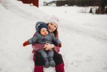 Sorridente Grande sorella holding bambino fratello al di fuori in il neve su freddo da — Foto stock