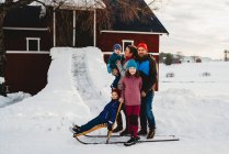 Bella famiglia in piedi vicino fienile rosso nella campagna norvegese nella neve — Foto stock