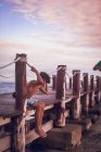 Pre teen boy seduto su un molo di legno su una spiaggia tropicale — Foto stock
