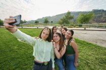 Un groupe d'amis essayant de prendre un selfie à travers leur téléphone portable dans — Photo de stock