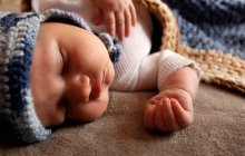 Süßer neugeborener Junge mit pummeligen Wangen schläft im Bett in Strickmütze — Stockfoto