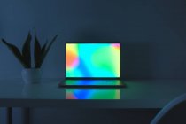 Laptop-Computer mit lebendigem Sceen, der auf einem Tisch steht, wenig blaues Licht. Konzept der Arbeit zu Hause, blaues Licht, minimalistischer Schreibtisch — Stockfoto