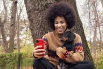 Uma garota cubana tirando uma selfie com seu dachshund no parque — Fotografia de Stock