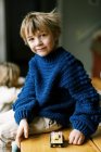 Menino em camisola de crochê caseiro brincando com blocos de construção — Fotografia de Stock