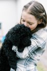 Женщина с любовью держит в руках своего нового черного миленького щенка — стоковое фото