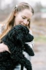Woman holding her black new cute poodle puppy in arms lovingly — Stock Photo