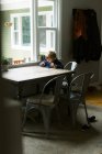 Маленький незалежний хлопчик використовує планшет для віддаленої школи за столом — стокове фото