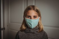 Menina na máscara olhando para a câmera durante a pandemia de Covid-19 — Fotografia de Stock