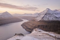 Montanhas nevadas subindo do oceano ao nascer do sol nas Ilhas Faroé — Fotografia de Stock