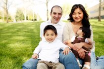 Familiy sitting in the grass in park — Stock Photo