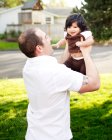 Отец держит дочь в воздухе в парке — стоковое фото