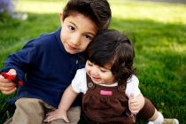 Jeune garçon et sa petite sœur regardant la caméra, dans le parc — Photo de stock