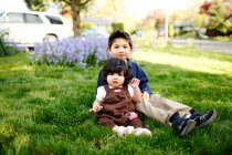 Young boy and his toddler sister looking at camera, in the park — Stock Photo