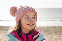 Молодая девушка, нахально смотрящая через плечо на пляже летом — стоковое фото