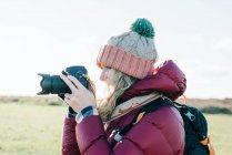 Woman holding a DSLR ready to take a shot whilst at the sunny beach — Stock Photo