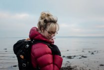 Mulher com uma mochila caminhando sozinha ao longo da costa inglesa — Fotografia de Stock