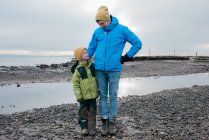 Padre e hijo estaban juntos en la playa cubiertos de barro sonriendo - foto de stock