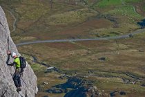 Hombre escalando cara de roca en Tryfan en el norte de Gales - foto de stock