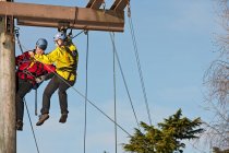 Two men working on wooden pole at high rope training exercise — Stock Photo