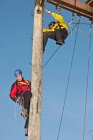 Two men working on wooden pole at high rope training exercise — Stock Photo
