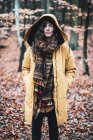 Strong young woman stands with hooded jacket in autumn leaves forrest — Stock Photo