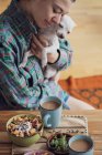 Happy person cuddles cute dog at home with coffee and breakfast — Stock Photo