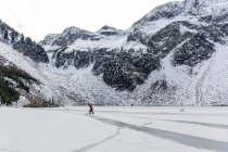 Man playing hockey near snowy mountains on frozen lake — Stock Photo