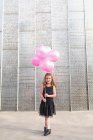 Красивая молодая женщина идет по улице с большими розовыми шариками — стоковое фото