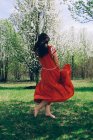 Frau in rotem Kleid tanzt zwischen den Bäumen — Stockfoto