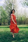 Donna in abito rosso che danza tra gli alberi — Foto stock