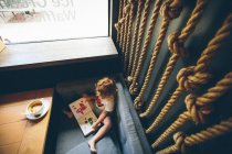 Девушка читает книгу в кофейне — стоковое фото