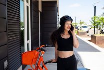 Молодая женщина с велосипедом и наушниками на улице — стоковое фото