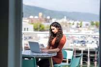 Jeune femme avec ordinateur portable et tasse de café sur la terrasse — Photo de stock