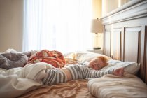 Menino da criança 3-4 anos de idade dormindo em pais bagunçados cama em luz bonita — Fotografia de Stock