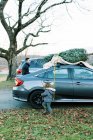 Человек погрузки елки на крыше автомобиля — стоковое фото