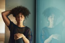 Woman with afro hair sitting in a shop window. She has her eyes closed and her hand is in her hair. — Stock Photo