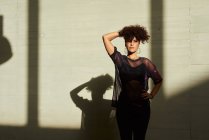 Портрет молодой женщины с афроволосами, ее тень проецируется сзади — стоковое фото