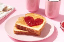 Toasts avec de la confiture de fraises en forme de coeur dessus comme un concept pour l'amour et la Saint-Valentin — Photo de stock