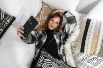 Jeune femme se détendre sur le canapé prendre selfie avec smartphone — Photo de stock