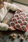 Child hands holding a tray of unbaked chocolate muffins about to bake — Stock Photo