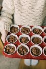 Kind hält ein Tablett mit ungebackenen Schokoladenmuffins in den Ofen — Stockfoto