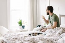 Homem hacing café da manhã na cama em casa — Fotografia de Stock