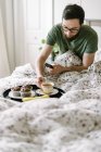 Man hacing breakfast on bed at  home — Stock Photo