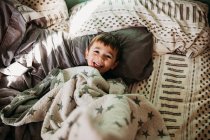 Симпатичный мальчик улыбается в постели — стоковое фото