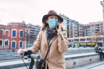 Young woman in protective mask and hat with scooter — Stock Photo