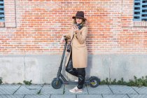 Beautiful young lady with scooter on the street — Stock Photo