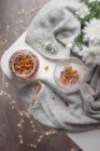 Una tazza di vetro con tè al fiore secco e un barattolo su un maglione grigio. — Foto stock