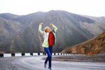 Mujer viajera baila en el camino de la montaña - foto de stock