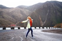 Mulher viajante dança na estrada da montanha — Fotografia de Stock