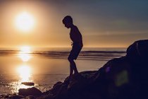 Kleiner Junge bei Sonnenuntergang am Strand — Stockfoto